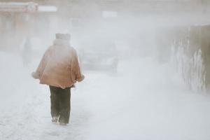 un hombre camina por la calle durante una ventisca y una nevada. foto