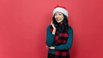 Smiling beautiful asia woman ware santa hat on red background. Concept of the New Year and Christmas Day. photo