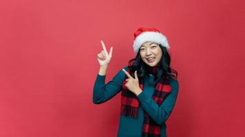Portrait photo positive lady in santa claus hat point index finger, copyspace direct way x-mas christmas newyear ads promotion wear style stylish sweater isolated over red background. Emotion smile