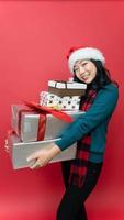 mujer joven feliz con gorro de Papá Noel con regalo de Navidad aislado fondo rojo. concepto del año nuevo y el día de navidad. foto