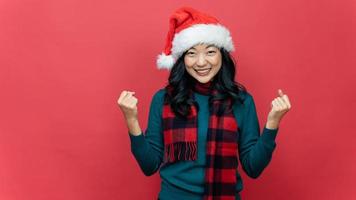 font view merry young woman wear xmas sweater Santa hat posing do winner gesture celebrate clench fists isolated on red background Happy New Year 2023 celebration holiday concept photo