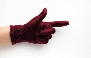 una mano en un guante médico quirúrgico color viva magenta, resaltada en un fondo blanco. producción de guantes protectores de goma. normas higiénicas y sanitarias foto