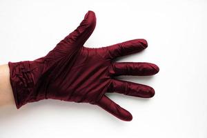 una mano en un guante médico quirúrgico color viva magenta, resaltada en un fondo blanco. producción de guantes protectores de goma. normas higiénicas y sanitarias foto