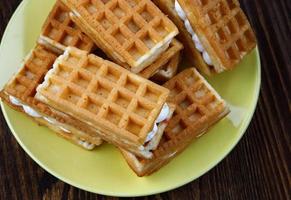 A pile of fresh Viennese waffles lie on a yellow plate. photo