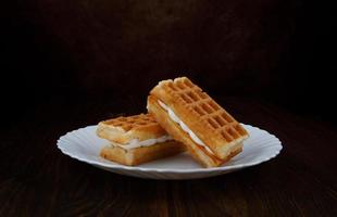 Fresh Viennese waffles with white cream on a white plate. photo