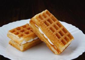 Fresh Viennese waffles with white cream on a white plate. photo