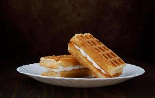 Fresh Viennese waffles with white cream on a white plate. photo