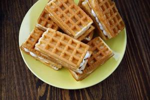 A pile of fresh Viennese waffles lie on a yellow plate. photo