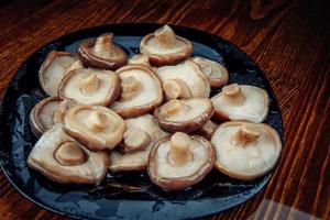 hermosos champiñones en escabeche en un plato de vidrio negro. comida sana del pueblo. champiñón de leche negra en escabeche. foto