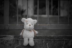 el oso de peluche solitario duerme en el piso de cemento para crear una postal de niños desaparecidos internacionales, corazón roto, solitario, triste, solo, lindo muñeco perdido no deseado. foto