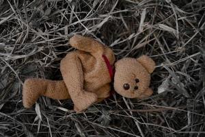 el oso de peluche solitario duerme en el suelo para crear una postal de niños desaparecidos internacionales, corazón roto, solitario, triste, solo, lindo muñeco perdido no deseado. foto