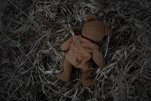 el oso de peluche solitario duerme en el suelo para crear una postal de niños desaparecidos internacionales, corazón roto, solitario, triste, solo, lindo muñeco perdido no deseado. foto