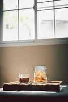 Glass of black coffee with jar of cookies in living room. photo