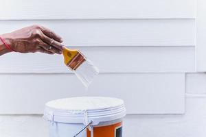 Painter hand holding paint brush with white paint. photo