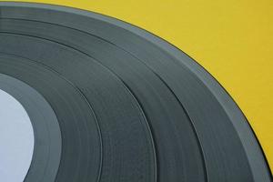 Close up of black old vinyl record play disc vintage on a yellow background with copy space for text. Retro LP history, nostalgia concept. Sound technology for DJ to mix music. Flat lay, top view photo