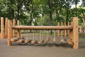 Rope bridge in outdoor modern children wooden playground in a public park of city. Eco-friendly lifestyle rest and childhood concept of safety environmentally infrastructure for kids. Funny adventure photo