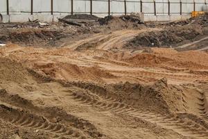 las líneas de marcas de neumáticos se forman en el fondo de arena seca. Huella de neumáticos de pista de maquinaria pesada. forma del vehículo. concepto de telón de fondo del sitio de construcción de carreteras. rastro del patrón de la rueda en el barro. textura de la naturaleza. foto