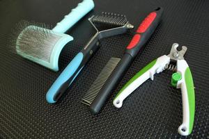 Set of professional instruments for grooming animals in salon on black table background. Clippers, brushes, combs, scissors. Pet care concept. Tools, equipment. photo