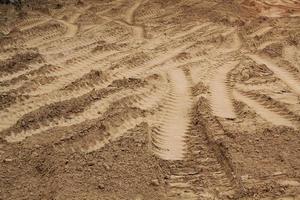 Tire track mark lines shape on dry sand background. Trail tyre imprint from heavy machinery. Vehicle shape. Road construction site backdrop concept. Trace of wheel pattern on mud. Nature texture. photo