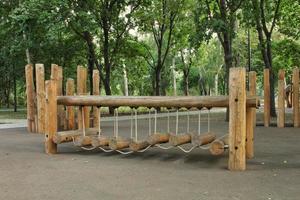 Rope bridge in outdoor modern children wooden playground in a public park of city. Eco-friendly lifestyle rest and childhood concept of safety environmentally infrastructure for kids. Funny adventure photo