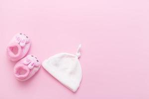 booties in the form of hares and a cap for a baby on a pink background with copy space photo