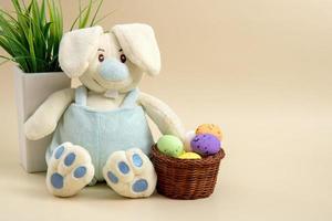 Bunny with a basket of Easter eggs on a light background with copy space photo