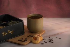 una taza de té y diferentes hojas de té con galletas en una mesa foto