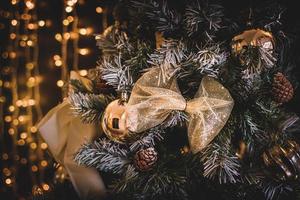 A closeup of golden Christmas ornaments and pine cones hanging on a tree with a bokeh background photo