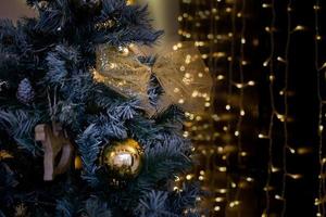 A closeup of golden Christmas ornaments and pine cones hanging on a tree with a bokeh background
