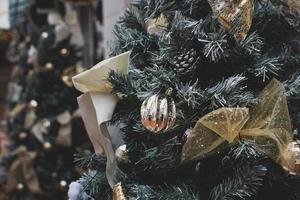A closeup of golden Christmas ornaments and pine cones hanging on a tree photo