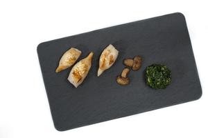 Flat lay image of sea food grilled squid with mushrooms and Swiss chards on a black stone plate photo