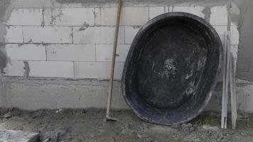 Mortar mixer and shovel with plasterboard. Leaning against the wall of a brick house. Construction background of house. photo