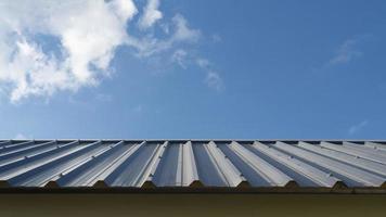 chapa de techo azul dispuesta en el techo. el techo a cuatro aguas de la casa está bellamente revestido. construcción de una casa bajo el cielo azul y nubes blancas. foto