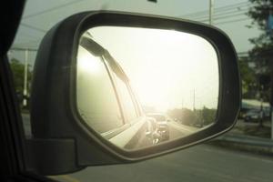 Wing mirror view of car on the road. With reflections of other cars lining the back in traffic jam or rush hours. Environment in the evening or morning time. photo