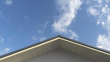 Gable corner of the roof of the central house used metal cheese roof. Under blue sky and white clouds. photo