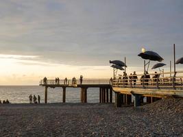 Pier on the beach with umbrellas. Pier in the rays of the setting sun photo
