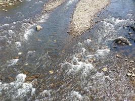 Rapid flow of the river. Big river, view from above. View from the bridge to the water. Thresholds on the water. photo