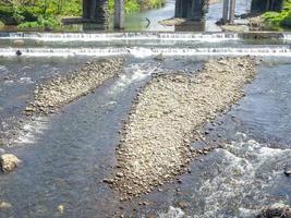 Rapid flow of the river. Big river, view from above. View from the bridge to the water. Thresholds on the water. Man-made rapids on the river. Technology on the water photo