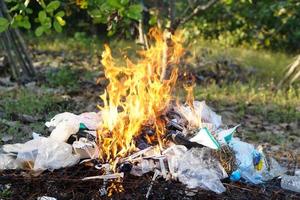 fuego quema montón de basura. concepto, incineración de residuos domésticos, papel, cartón, restos de comida, plástico, ramitas y otros residuos que provocan la contaminación del aire. manejo de basura foto