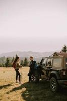 Young couple relaxing on a terrain vehicle hood at countryside photo