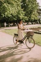 Young woman with white bichon frise dog in the basket of electric bike photo