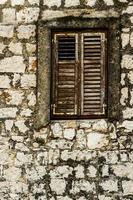 Stone wall and window with closed wooden shutters photo