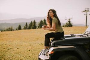 Young woman relaxing on a terrain vehicle hood at countryside photo