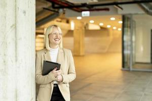 Businesswoman with digital tablet on modern office hallway photo