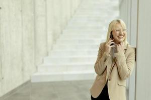 Businesswoman using mobile phone on modern office hallway photo