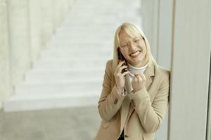 mujer de negocios que usa teléfono móvil en el pasillo de la oficina moderna foto