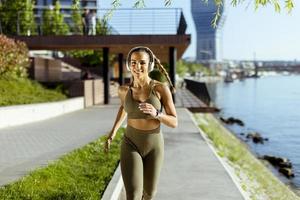 Mujer joven haciendo ejercicio para correr por el paseo fluvial foto