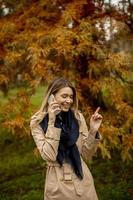 hermosa joven usando teléfono móvil en el parque de otoño foto