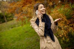 Young woman using mobile phone in the autumn park photo