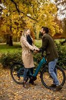 Young couple in the autumn park with electrical bicycle photo